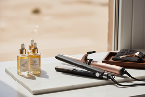 Close-up of premium hair care products like hair straighteners, curlers, and serums arranged neatly on a marble or wooden surface. Soft natural lighting, elegant and minimalist UAE style, focus on products only, 16:9 banner format, premium and aspirational feel.
